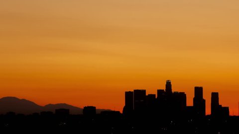 4K Time lapse pan shot sunrise over downtown Los Angeles skyline silhouette with red and orange colored sky