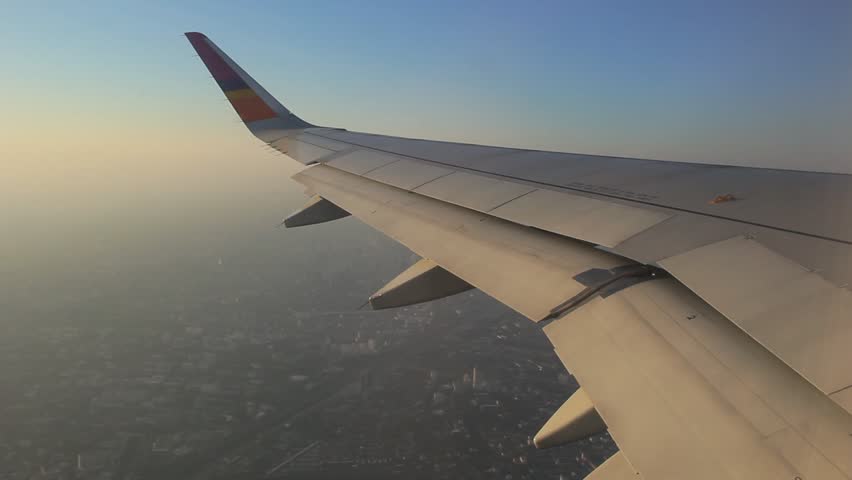 Airplane wing was taken from a window seat in flight in the morning with warm sunshine.