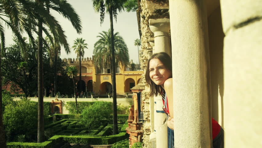 Young pretty woman looking at Alcazar view from terrace in Seville, Spain
