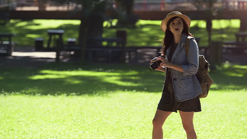 Trendy young tourist girl taking photos in a park