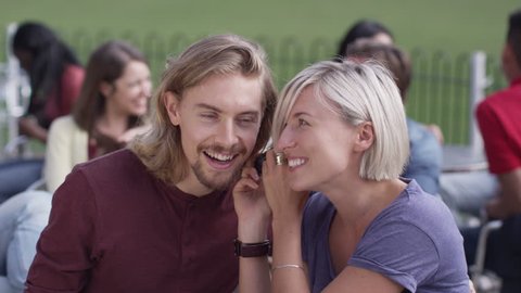 4K Attractive young couple listening to music through headphones at outdoor cafe