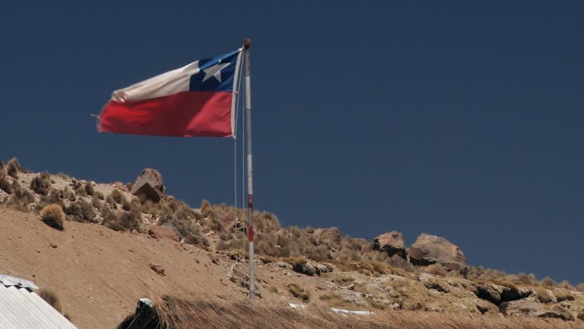 PARINACOTA, CHILE - OCTOBER 22, 2013: Chilean National flag waves over the buildings of Parinacota village in Lauca National Park, Chile. Parinacota village is located at 4400 meters above sea lavel.