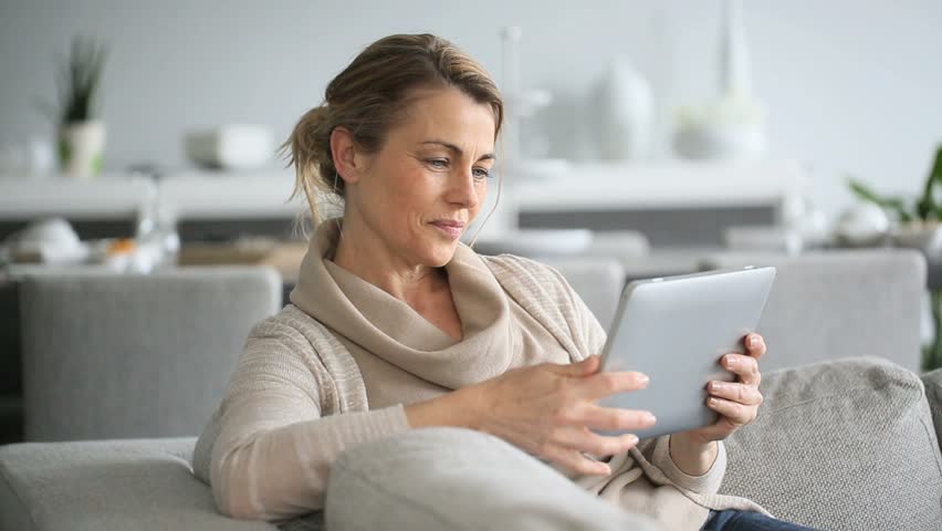 Mature woman sitting in sofa and websurfing on digital tablet Royalty-Free Stock Footage #9572177