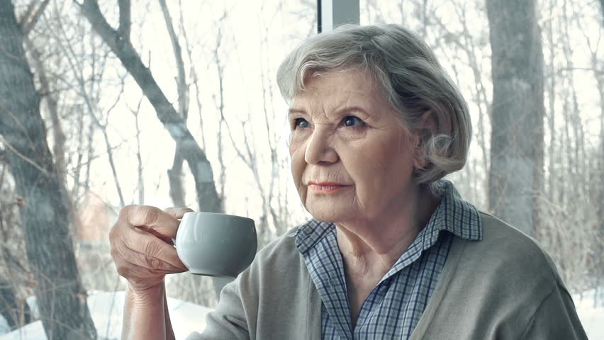 Side view of senior lady having tea and pondering