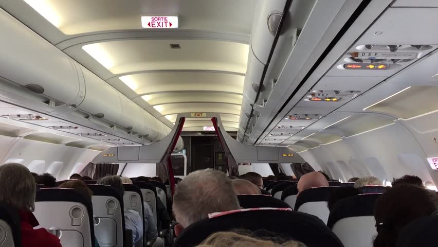 Jet airplanes interior view with unrecognizable peole seated while verification of air turbolences.