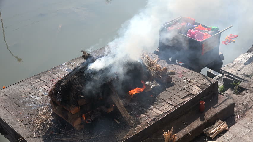 Public cremation of a deceased person at the ghats of the Pashupatinath temple complex in Kathmandu, Nepal.