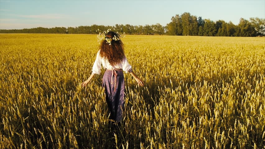 Slavic girl in national costume among the wheat