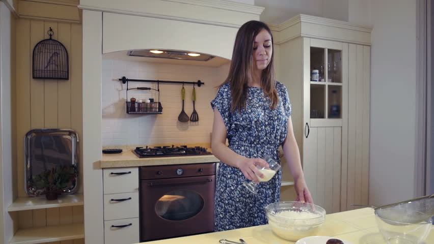 Young woman adding milk to a bowl and mixing it