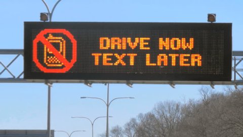 Highway sign reads: DRIVE NOW TEXT LATER, traffic timelapse