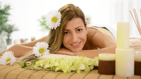 Cute young woman lying on a towel during a skincare treatment at a spa.