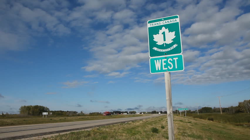 Trans Canada Highway 1 sign in Saskatchewan, Canada. Red truck passes.