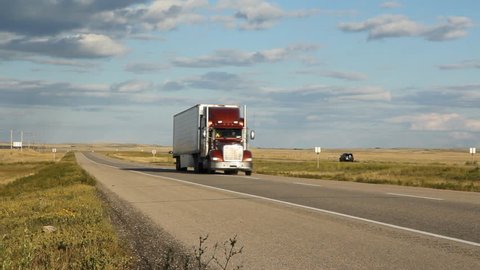 Red truck and car passing on the highway. Saskatchewan, Canada. Beautiful prairie landscape.