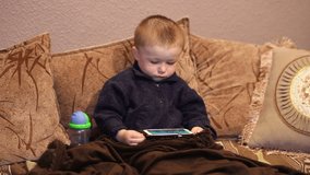 Little boy sitting on the couch and watching a cartoon on your smartphone
