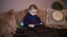 Little boy sitting on the couch and watching a cartoon on your smartphone
