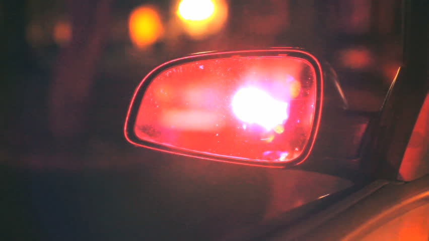 Police flashing lights in car rear view mirror at night