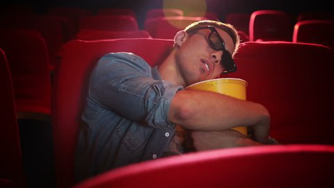 Young man asleep at the cinema wakes up startled