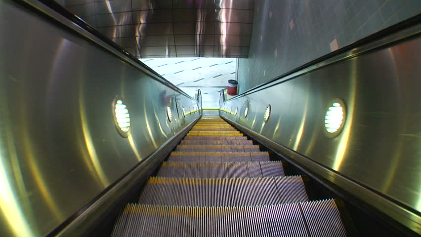 Fisheye shot on a downward escalator as two men pass.
