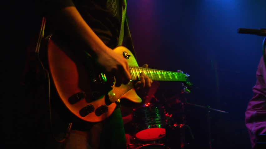 This is a close up shot of a man playing a guitar at a rock concert at a popular