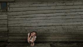 Girl sitting near a wooden house