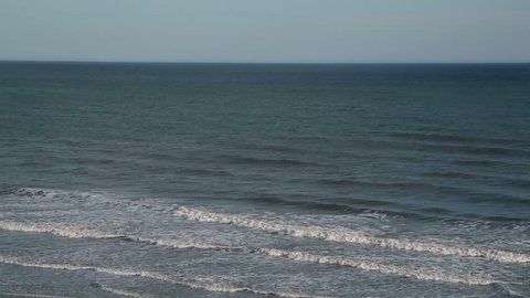 Gentle waves and clear sky viewed from a beach condominium.