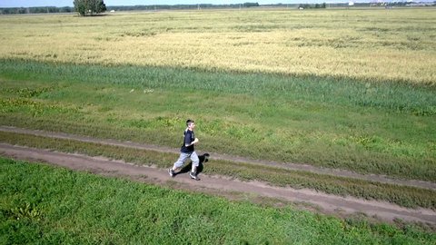 Aerial. Running athlete man. Male runner sprinting during outdoors training Athletic fit young sport fitness model on road outside in green field. 