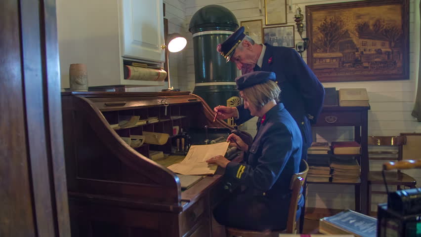 Train timeline is stamped and given froword. Slow motion RAW footage of a woman seating at the wooden table and working on train time line in the train museum.