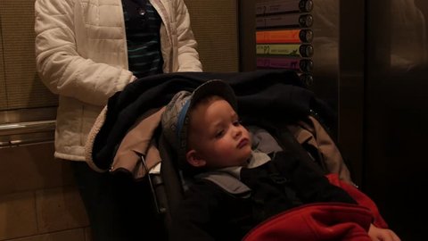 A young family exits an elevator with a toddler in a stroller