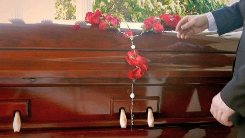 Casket at funeral service ceremony, remembrance roses fall in slow motion on coffin 