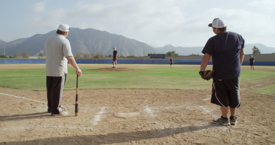 Wide shot of a coach teaching his players baseball techniques in the infield such as fielding ground balls