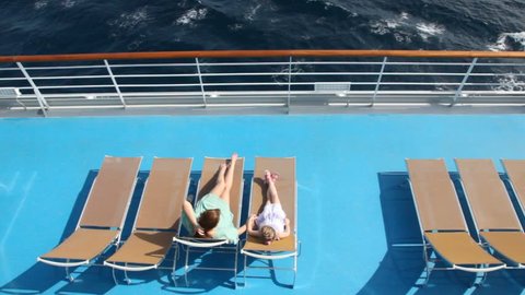 woman and girl are lying on the deck chairs on deck of ship