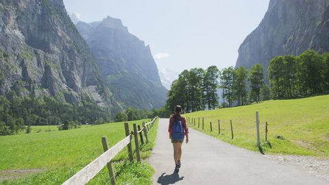 People walking in Switzerland alps. Woman hiker tourist hiking on hike in Swiss alpine nature landscape in Lauterbrunnen valley in Bernese Oberland, Schweiz, Europe. RED EPIC SLOW MOTION.