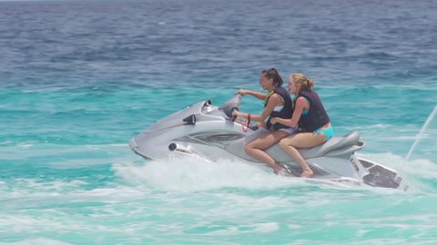 Young Fit Women Friends Having Fun Riding Jet Ski In The Sea