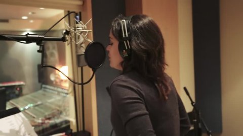 Shot of a female singer recording at a Music Studio