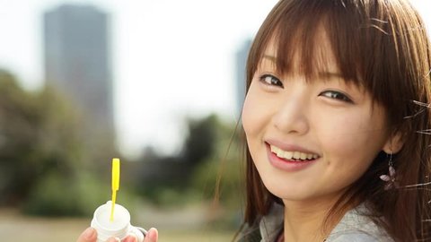 Attractive young Japanese girl portrait blowing soap bubbles Adlı Stok Video