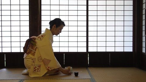 Mature Japanese woman in a kimono preparing green tea in a traditional house