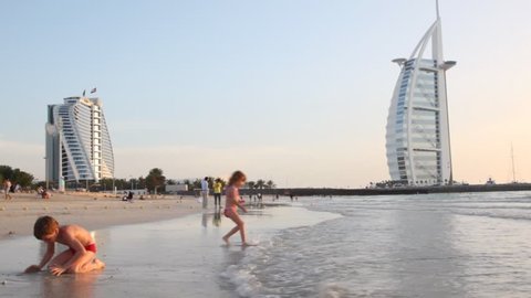 DUBAI - APRIL 17: Children playing on beach near Burj Al Arab, five-star hotel, at sunset on April 17, 2010 in Dubai, United Arab Emirates. At 321 m (1,053 ft), it is the fourth tallest hotel in the world
