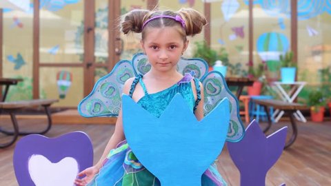 Little girl in fairy costume depict bird in children cafe on veranda