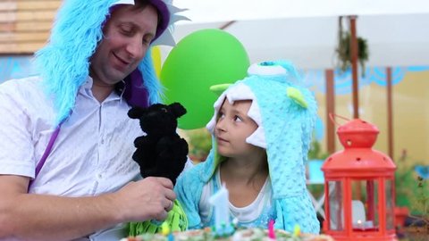 Father with daughter in monster costumes with dog toy celebrate birthday in cafe