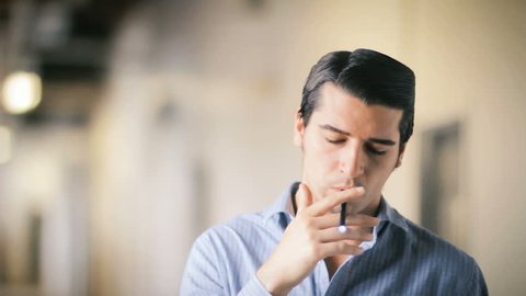 Handsome young man smoking electric e cigarette vapor indoors 