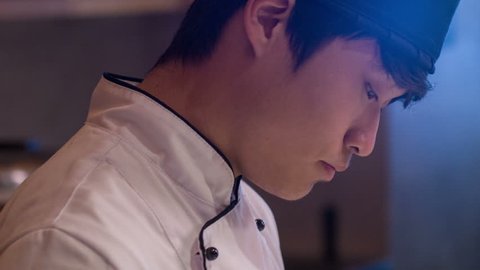 Young Japanese chef. Vertical dolly shot of young concentrated chef standing in restaurant kitchen preparing sushi Stock Video