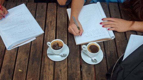 Above angle view of casual entrepreneur woman team/student team, writing down the brainstorming session, wile in a coffee meeting at cafe. 