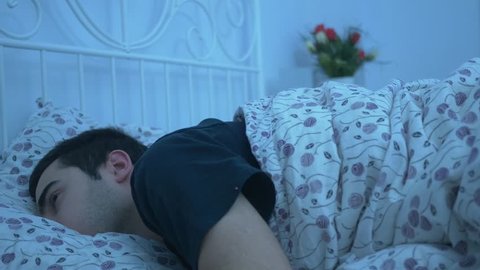 Young attractive adult alone laying in a comfortable clean bed having trouble to fall asleep. Insomnia, or sleeplessness, is a sleep disorder in which there is an inability to fall asleep.
