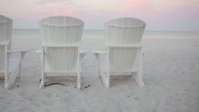 Adirondack chairs on the white sand beaches of Florida's Gulf of Mexico during a beautiful sunset.