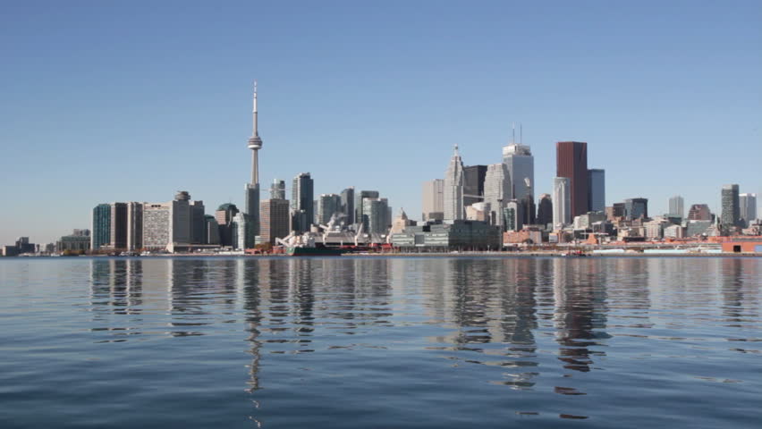 Toronto waterfront. Wide. View of Toronto from the east. Sunny autumn day with glassy water. Tower crane rotates in the distance. Toronto, Ontario, Canada. 