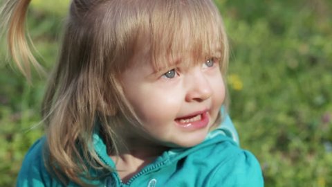 Little girl child sneezes in nature and expresses emotions