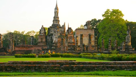 Video 1080p - Ancient Buddhist temple ruin in Sukhothai Thailand. Foundations. columns. and some complete spires and sculptures can be seen amongst an immaculately landscaped park.