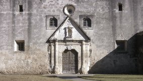 Video pan up door to cross old Spanish Mission Concepcion San Antonio, Texas. Built early 1700â€™s by missionaries from Spain and local Indians. Bell tower with cathedral, rock well and stone walls. 