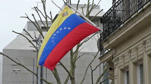 A Venezuelan flag on the pole on the side of the street. Waving on the breeze of the wind