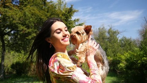 Beautiful brunette girl with little pet dog have fun posing in park