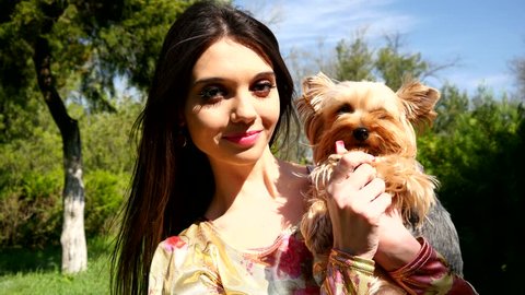 Beautiful brunette girl with little pet dog have fun posing in park